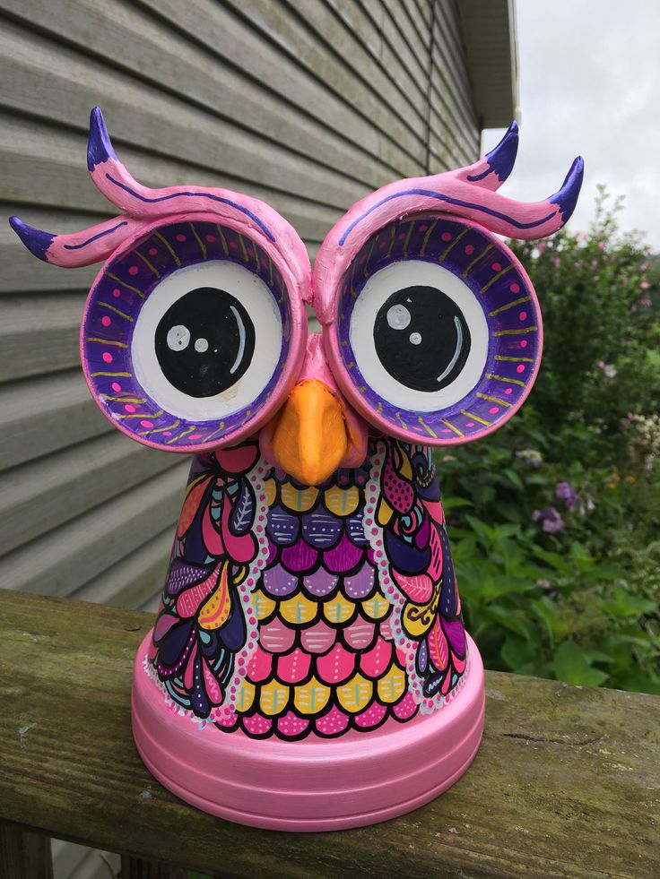 an owl figurine sitting on top of a wooden fence