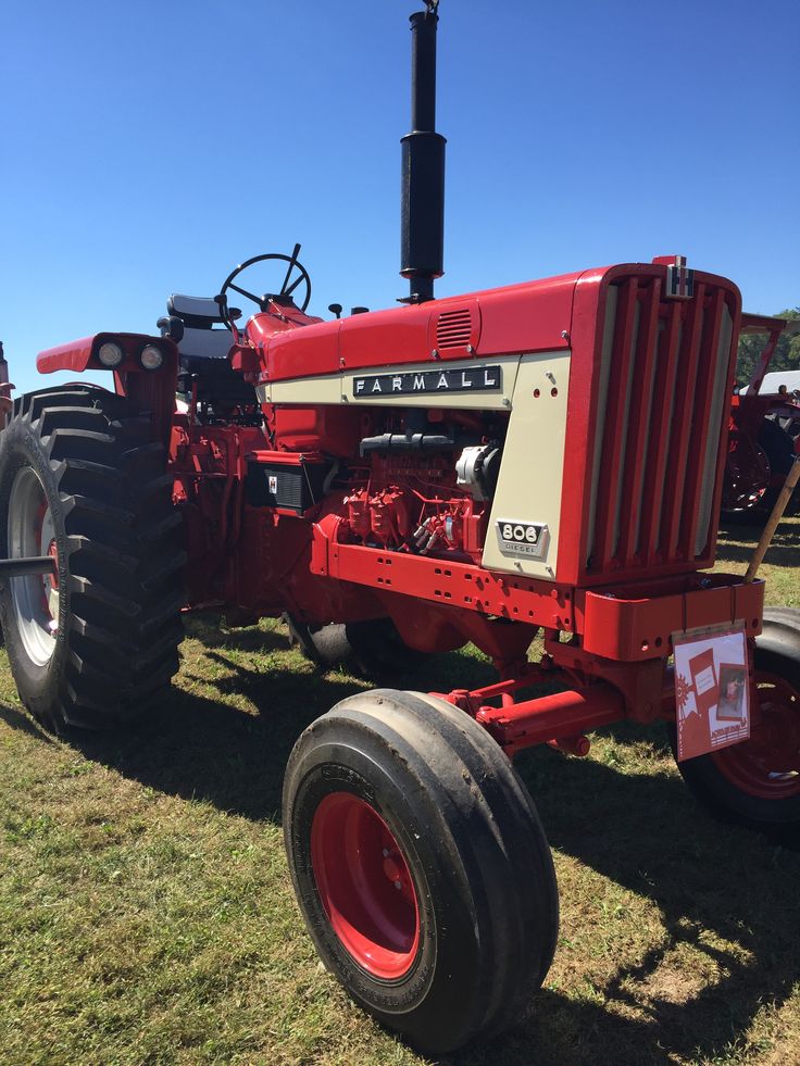 an old red farmall tractor parked in the grass