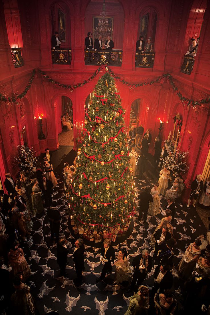 a large christmas tree is lit up in the middle of a room filled with people