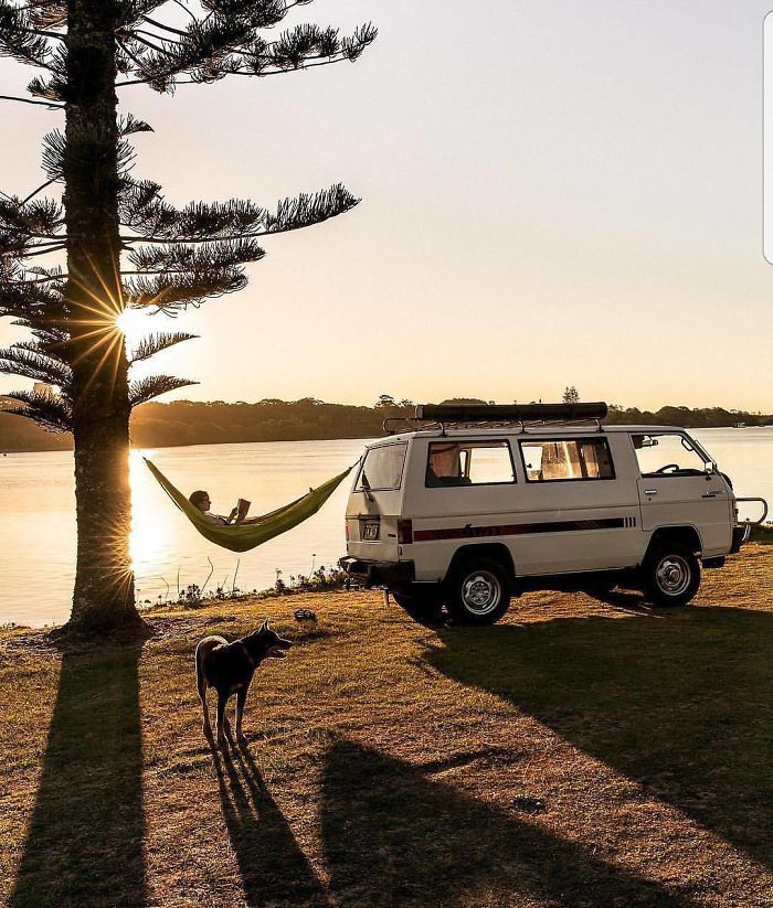 a white van parked next to a lake with a hammock hanging from it's roof