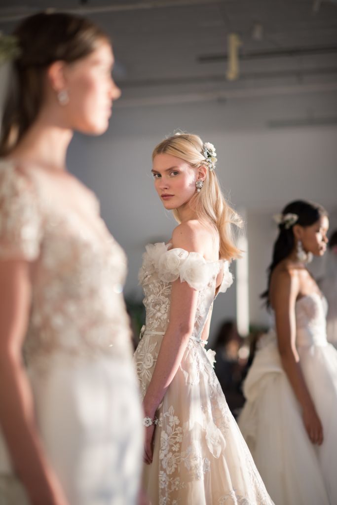 two women in wedding gowns standing next to each other and looking at each other