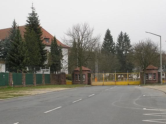 an empty street with some buildings in the back ground and trees on either side of the road