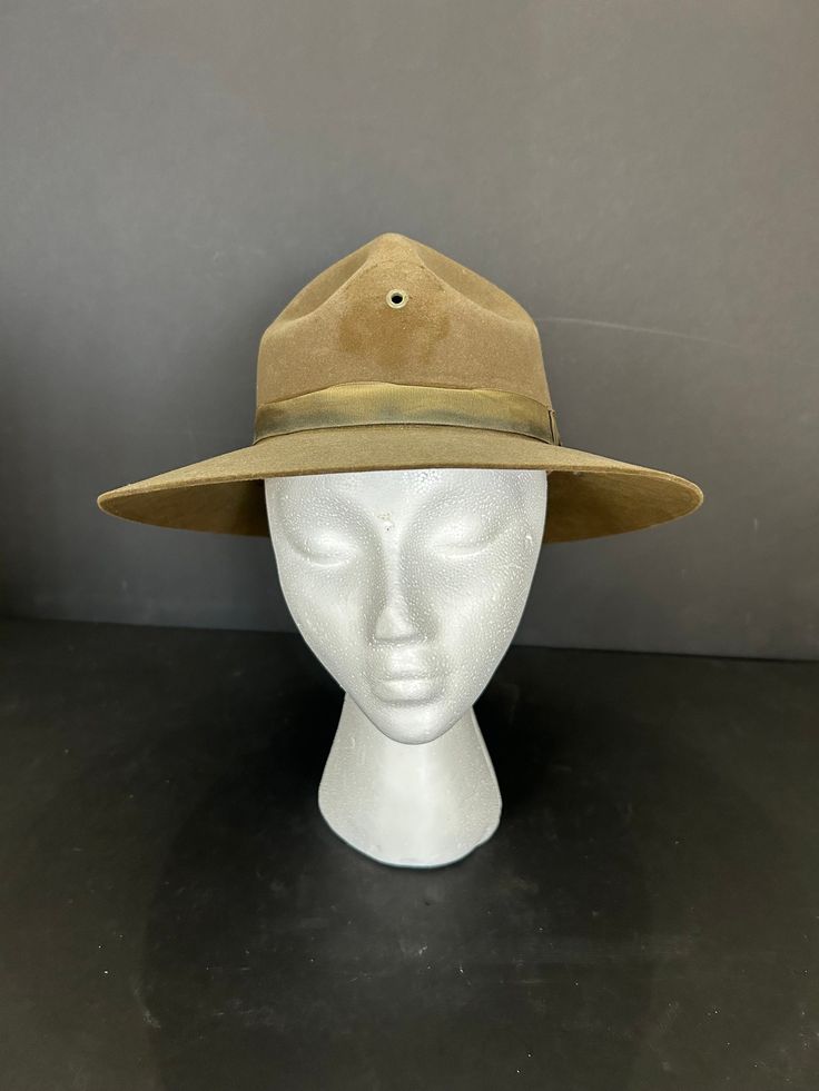 This vintage hat has a brown and olive green tint. Some call the Campaign Hat the 'Smokey the Bear' hat or the Forest Ranger hat, others the Drill Instructor hat. You also see this style mentioned in literature as a 'Baden-Powell' hat. This distinctive hat historically is associated with the campaigns of WWI or the American Boy Scouts (Baden-Powell is the founder).  Size 7 and about 5 inch Montana peak crown 3 inch flat, raw edge brim. Heavy and well made of 100% Wool with felt 4-pinch Montana p Retro Brown Hat For Country Events, Adjustable Brown Hats For Hunting, Brown Military Brimmed Hat, Brown Brimmed Costume Hat For Outdoor Use, Brown Brimmed Outdoor Costume Hat, Military Style Brown Hat With Curved Brim, Brown Military Hat With Curved Brim, Brown Short Brim Hunting Hat, Classic Khaki Cap