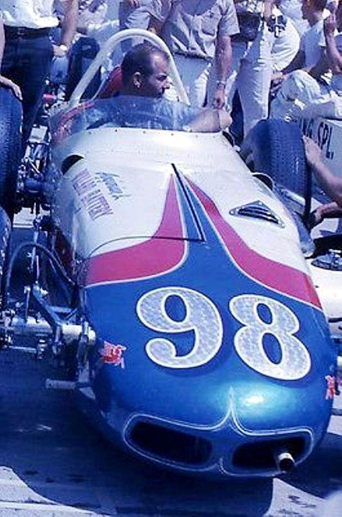 a group of men riding on the back of an old race car