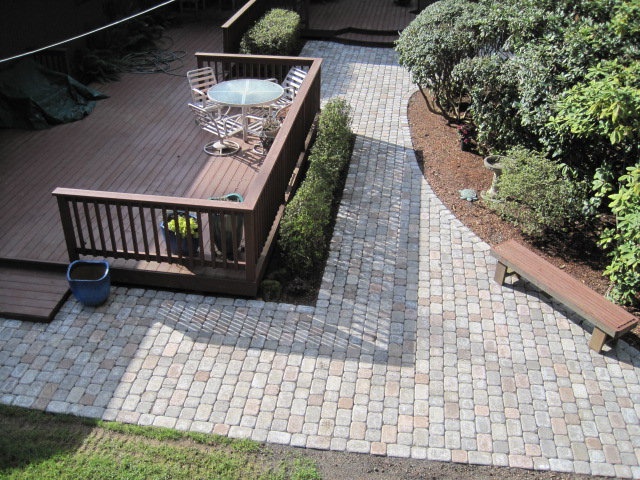 an aerial view of a deck and patio area with benches, trees, and bushes