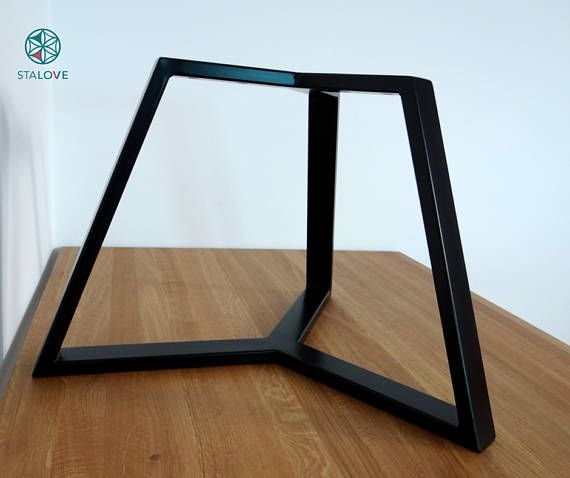 a wooden table with a black metal frame on it's side and a white wall in the background