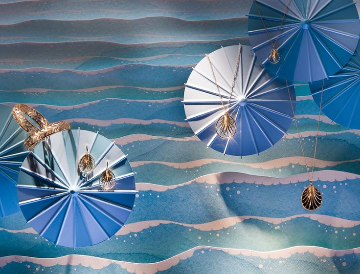 three blue umbrellas hanging from strings in front of an ocean scene with gold accents