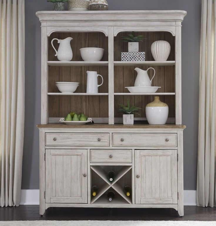 a white china cabinet with glass doors and shelves on the top, filled with dishes