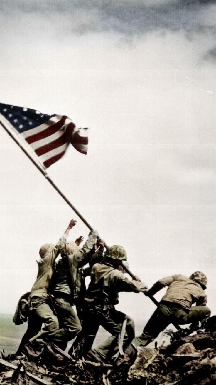 soldiers raising the american flag on top of a hill