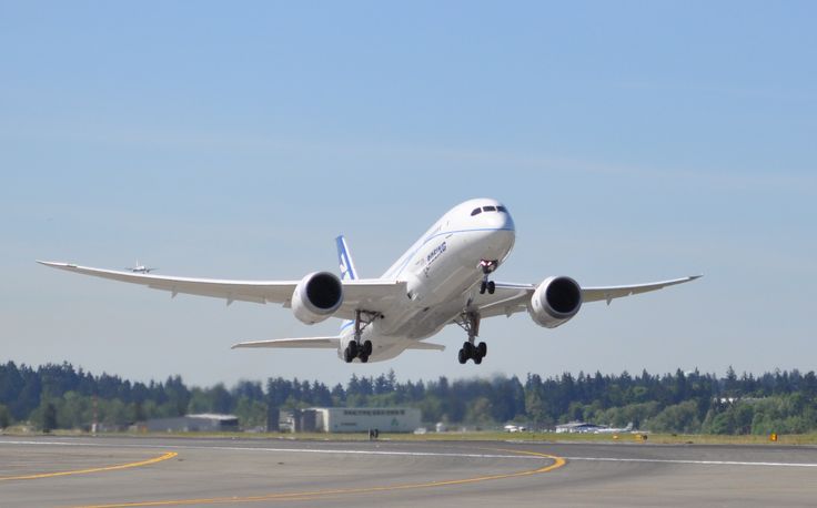 an airplane is taking off from the runway in front of some trees and blue sky