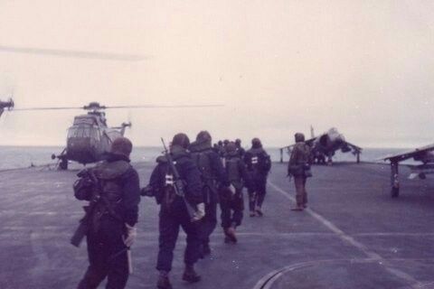 several people are walking towards an airplane on the runway near water and planes in the background