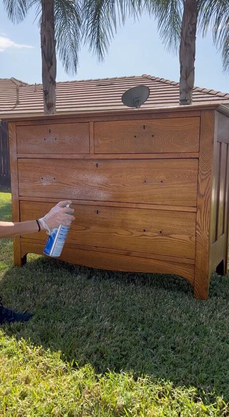 a person is painting the outside of a wooden chest with blue paint on it and palm trees in the background