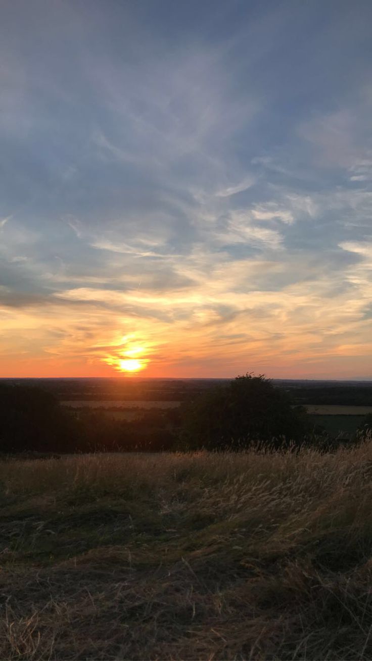 the sun is setting over an open field