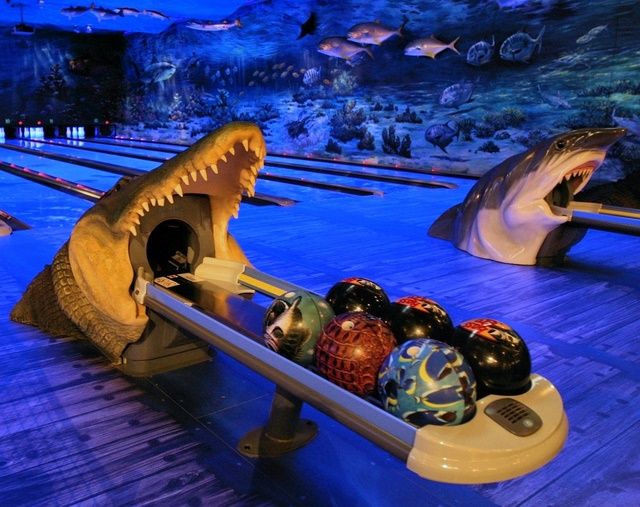 bowling balls are being thrown into the water by an alligator's mouth in a bowling alley