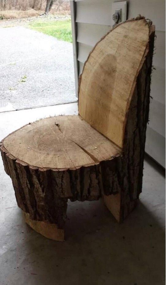 a chair made out of wood sitting on top of a cement floor next to a garage door