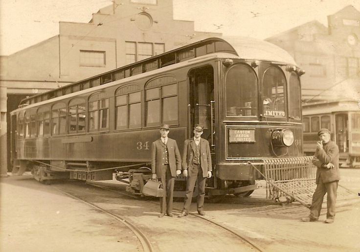 three men standing in front of a train car on the tracks near another man and woman