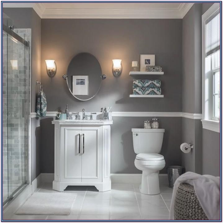 a white toilet sitting next to a bathroom sink under a round mirror in a bathroom