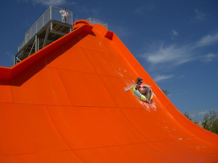 a man riding a surfboard on top of an orange ramp