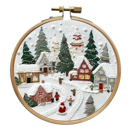 a cross stitch christmas scene with houses, trees and snow on the ground in front of a white background