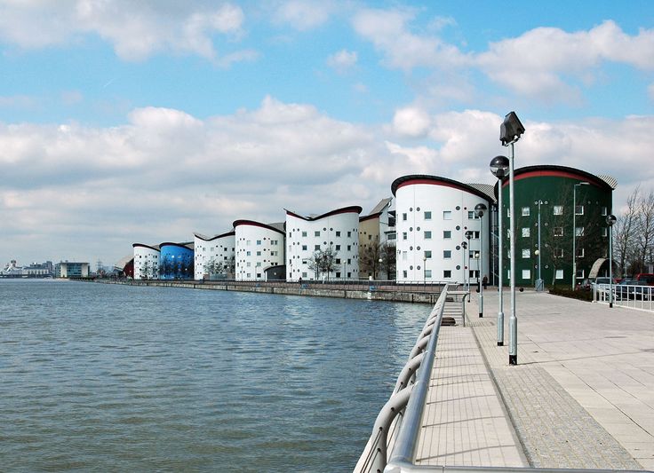 a row of white buildings sitting next to a body of water on top of a pier