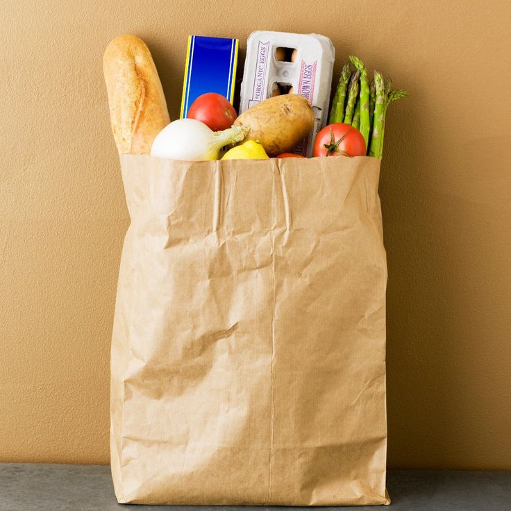 a brown paper bag filled with groceries sitting on top of a counter next to a wall