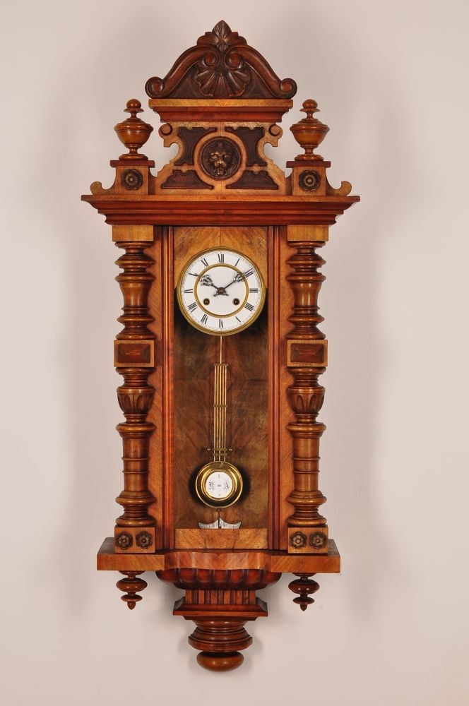 an ornate wooden clock mounted to the side of a wall