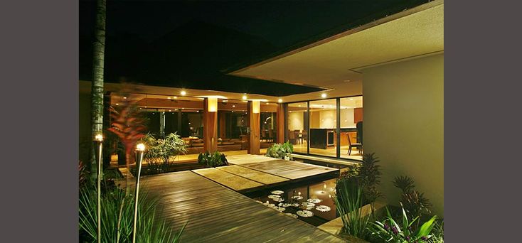 an outdoor area with lights and water features in the night time, along with bamboo trees