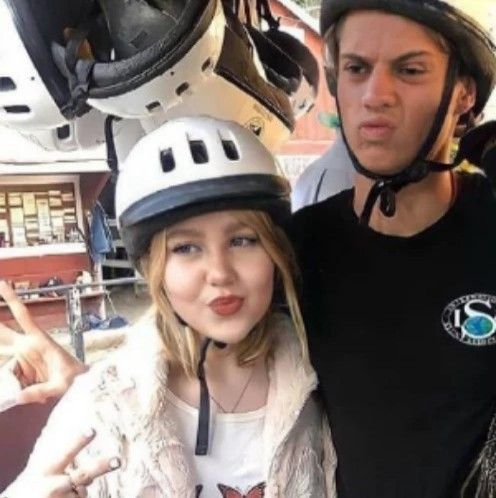 two people standing next to each other with helmets on their heads and one person pointing at the camera