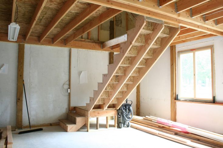 an unfinished room with stairs and wood flooring