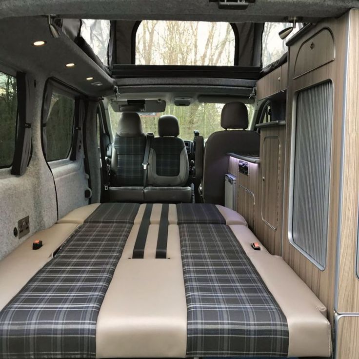 the interior of a van with plaid bedding and black trim on the front seats