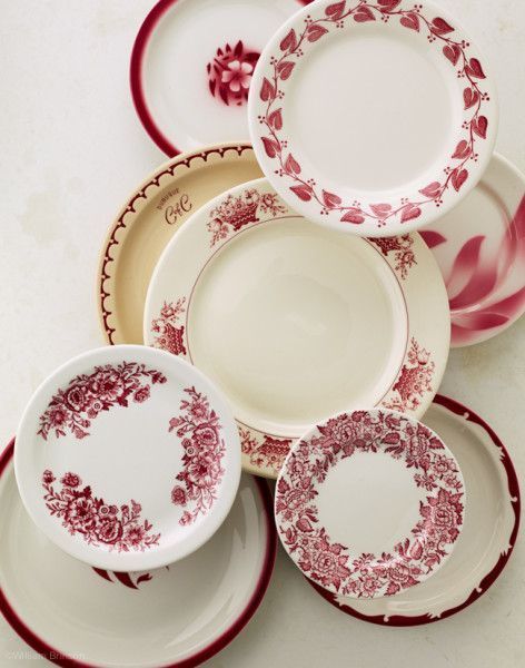 a pile of red and white plates sitting on top of a table next to each other