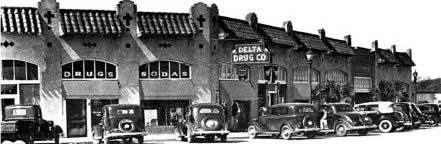 an old black and white photo of cars parked in front of a building