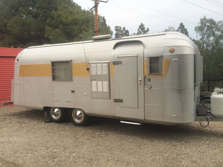 an old trailer is parked in the gravel