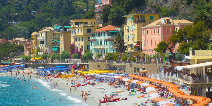 many people are on the beach with umbrellas and inflatable chairs near the water