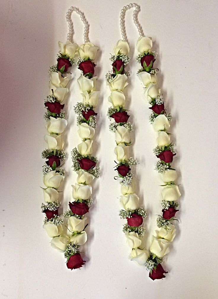 two white and red flowers are attached to necklaces