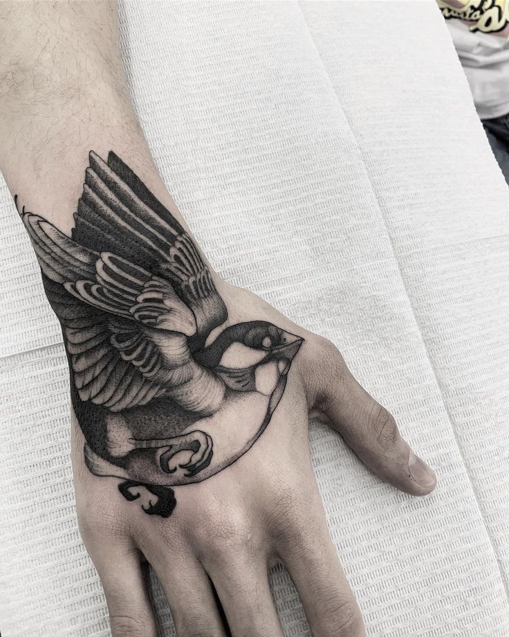 a hand with a bird tattoo on it