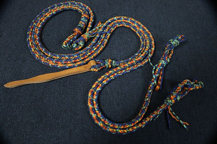 a pair of scissors sitting on top of a blue surface next to a multicolored rope