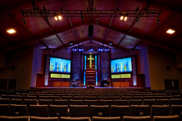 an empty auditorium with rows of seats and large screens