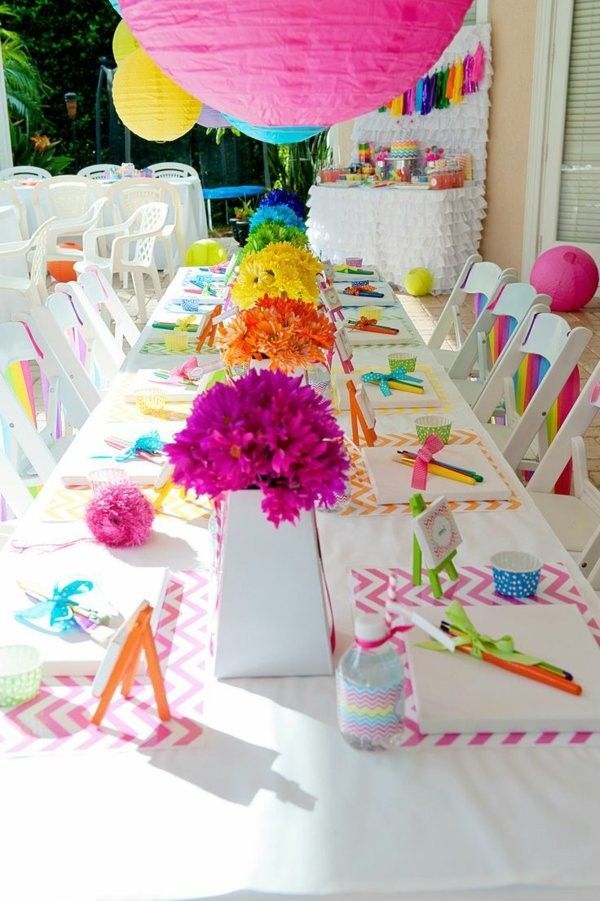 the table is decorated with colorful flowers and tissue paper pom poms for decoration