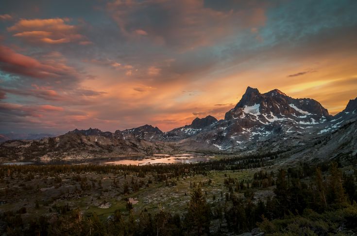 the mountains are covered in snow as the sun is setting over them and there is no image to describe