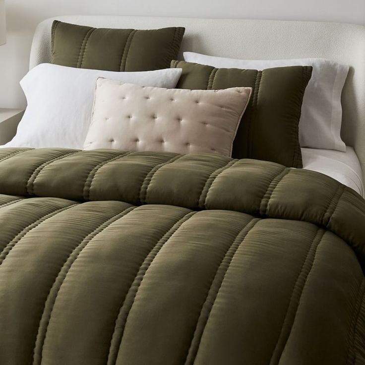 a bed with green comforter and white pillows