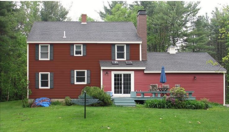 a red house in the middle of a lush green yard