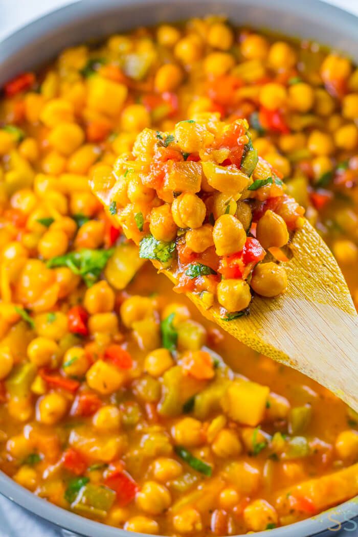 a wooden spoon full of chickpeas and carrots in a white saucer