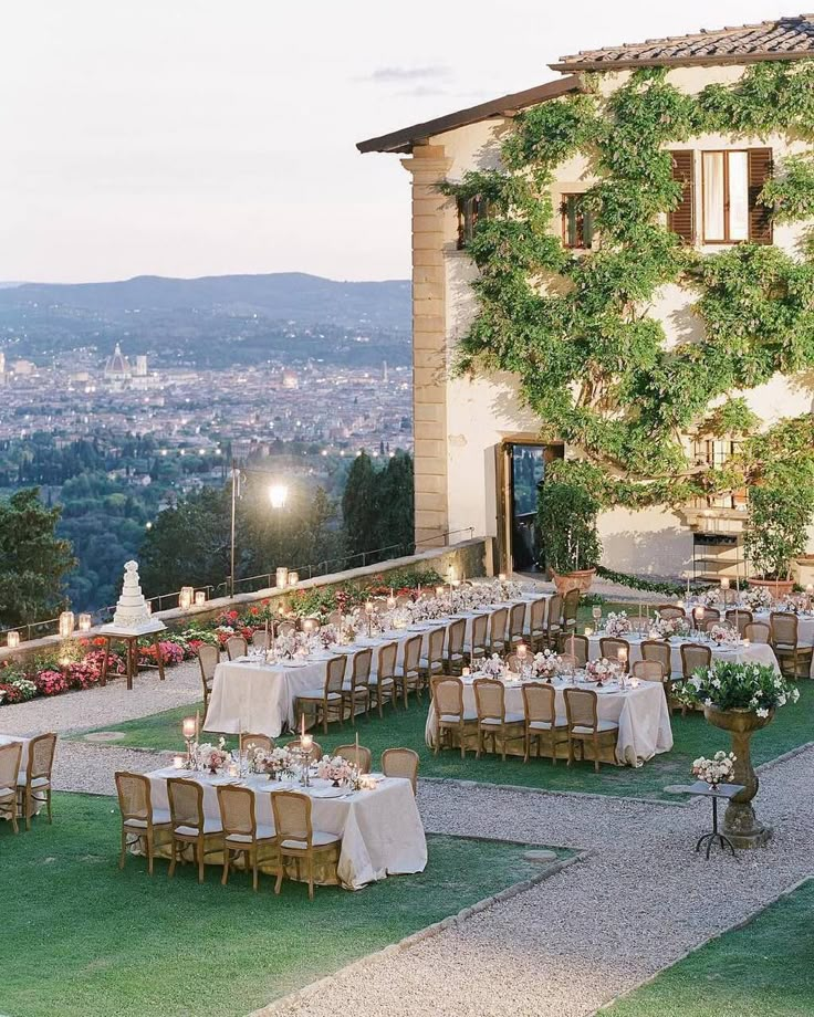 an outdoor dining area with tables and chairs set up for formal dinner overlooking the city