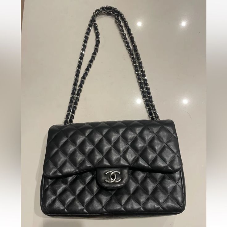 This Chanel Shoulder Bag Is A Timeless Classic, Crafted From Black Quilted Lambskin Leather With Silver Hardware Accents. The Authentic Bag Id# 19277509 The Bag Features A Rectangular Shape With A Turn Lock Closure And Double Handles For Easy Carrying. It Has A Large Size With A Depth Of 3.75 Inches, A Width Of 12 Inches, And A Height Of 8 Inches. The Bag Has Four Inside Pockets And One Outside Pocket, Providing Ample Space For Your Essentials. It Also Comes With A Chain Strap That Can Be Adjusted To A Drop Of 12.75 To 23.5 Inches. The Bag Is Adorned With Silver Stitching Accents And Chanel's Signature Burgundy Leather Lining. This Classic Double Flap Shoulder Bag Is A Must-Have For Luxury Office Bag With Double Flap, Elegant Double Flap Office Bag, Elegant Flap Bag With Cc Turnlock For Everyday Use, Luxury Business Shoulder Bag With Cc Turnlock Closure, Elegant Double Flap Bag For Everyday Use, Elegant Leather Bag With Double Flap, Luxury Double Flap Shoulder Bag For Formal Occasions, Elegant Double Flap Leather Bag, Luxury Shoulder Bag With Cc Turnlock Closure