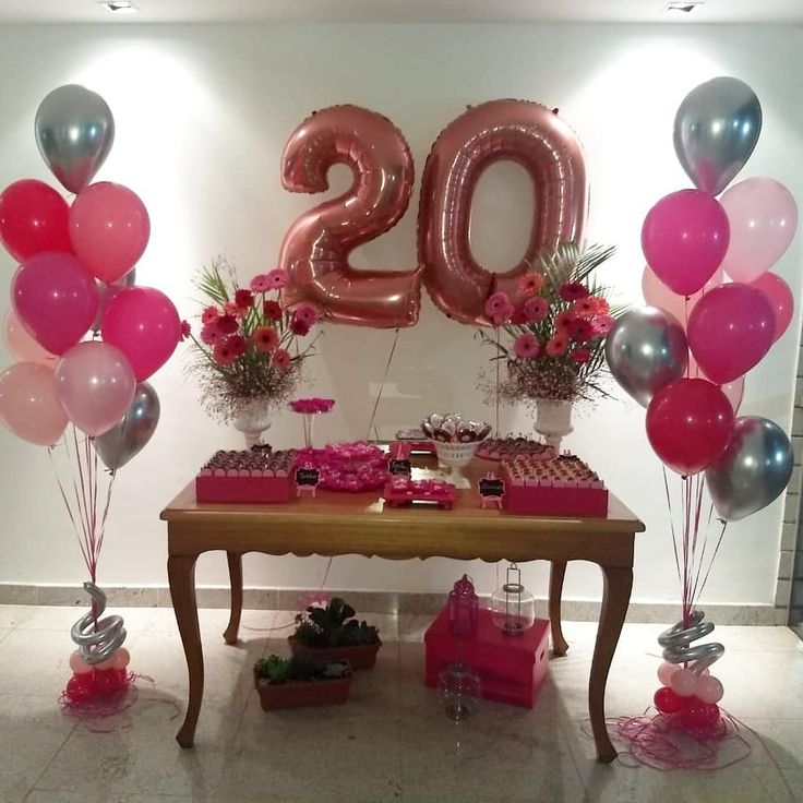 a table topped with lots of pink and silver balloons next to a number twenty sign