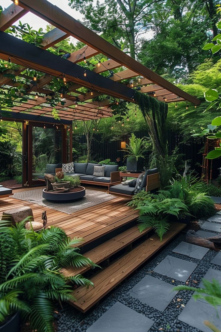 Chic backyard oasis featuring wooden decking, cozy seating, hanging lights, and lush greenery, perfect for outdoor living and backyard landscaping ideas. Backyard Patio Oasis Ideas, Big Backyard Design Layout, Backyard Design Layout On A Budget, Private Master Patio, Garden And Patio Ideas, Backyard Landscaping Full Sun, Backyard Pagoda Patio Ideas, Small Backyard With Deck Ideas, Front Yard Patio Designs