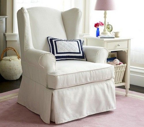 a white chair sitting in front of a window next to a pink rug on top of a hard wood floor