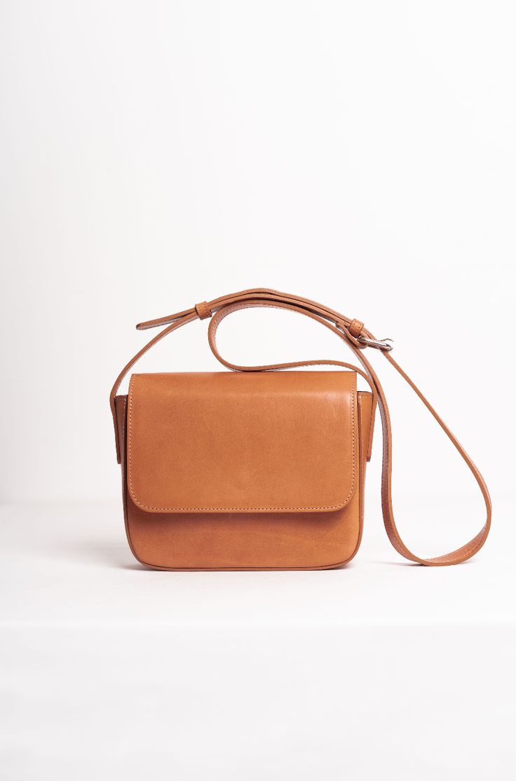 The Palmar is a leather crossbody bag that features a roomy compartment, a slim interior pocket, and one exterior pocket. It is handmade from vegetable-tanned leather and has a front flap closure with a magnetic snap. The leather strap can be adjusted to suit your preferred length, and the bag has a beige cotton lining. The exterior pocket allows you to keep your wallet and phone handy, yet safe at the same time. The sides and edges of the leather are delicately painted. This bag is joyfully man Modern Cognac Saddle Bag With Detachable Strap, Classic Flap Bag With Detachable Strap For Daily Use, Classic Everyday Shoulder Flap Bag, Modern Brown Flap Bag With Adjustable Strap, Brown Saddle Bag With Top Handle And Magnetic Closure, Brown Top Handle Saddle Bag With Magnetic Closure, Brown Flap Bag With Detachable Strap For Everyday, Everyday Brown Flap Bag With Detachable Strap, Classic Brown Saddle Bag With Adjustable Strap