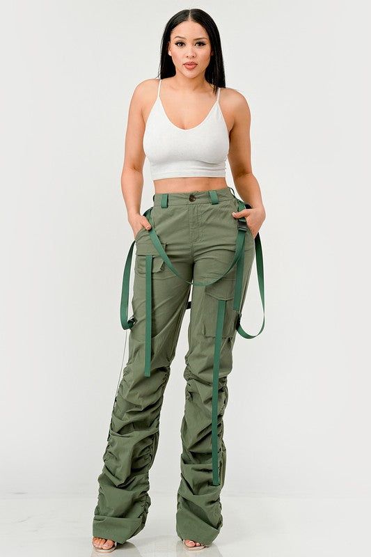 This distinct fashion choice merges the practicality of traditional utility wear with a touch of contemporary finesse. The pants are an ode to the functional attributes of cargo garments, designed to be robust with ample pocket space for practical use. The ruched detailing along the legs introduces a unique aesthetic twist, creating a gathered, textured effect that adds visual interest and a flair of modern sophistication. The inclusion of sleek, tonal belt straps further accentuates the waistli Spring Combat Cotton Cargo Pants, Spring Cotton Combat Cargo Pants, High Waist Combat Cargo Pants With Pockets, Combat Pants With Cargo Pockets For Fall, Combat Style Bottoms With Multiple Pockets For Fall, Utility Parachute Pants With Functional Pockets, Combat Bottoms With Multiple Pockets For Fall, Spring Combat Pants With Pockets, Spring Combat Cotton Pants